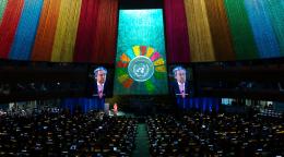 The hall of the general assembly lit up by the SDG colours and a projection of the secretary-general