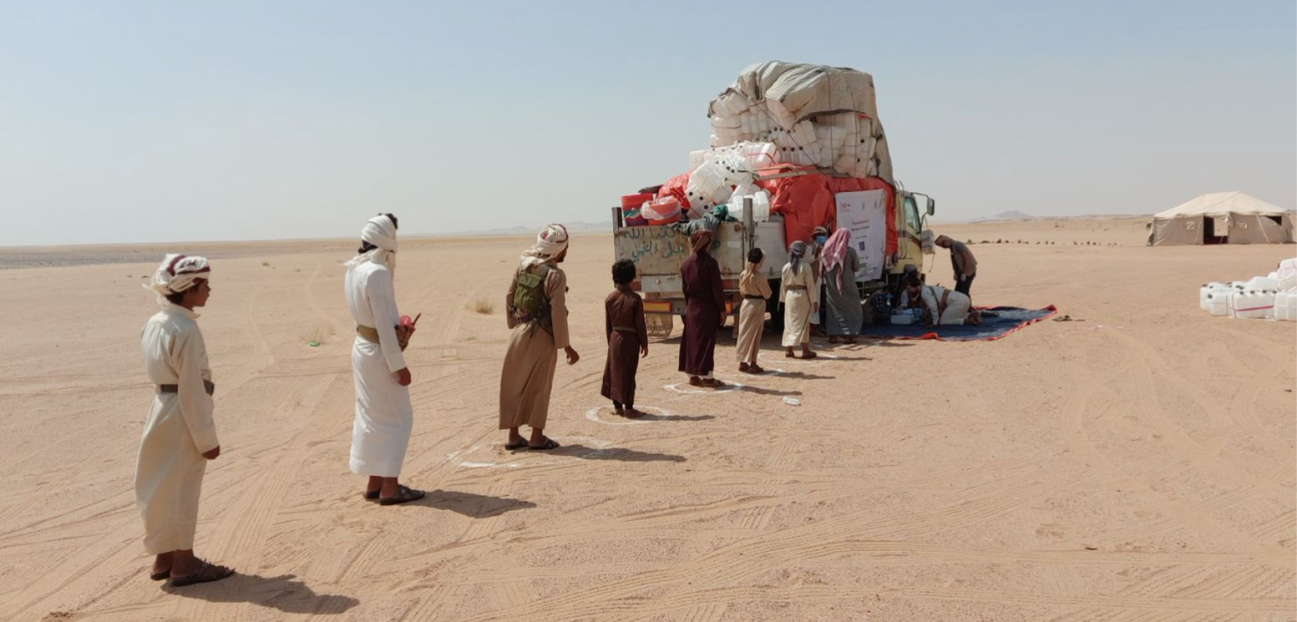 Displaced people stand two meters apart, keeping their distance as they wait in the rapid-response distribution line in Al Jawf. 