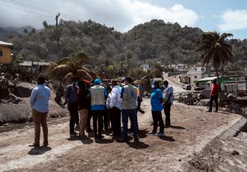 Un equipo de funcionarios y funcionarias de la ONU examinan las secuelas de la erupción volcánica.