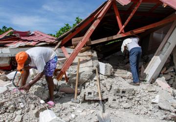 两名男子在7.2级地震后一栋倒塌的建筑物废墟中展开搜救工作。