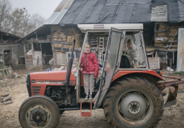 فتاتان تركبان جرارًا في مزرعة.