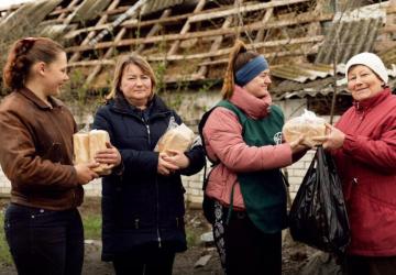 一名志愿者向妇女们分发面包。
