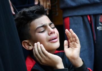 A young boy, with his hands to his face, cries in Gaza City.