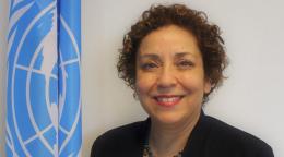 صورة رسمية لسيزين سنان أوغلو وهي تقف أمام علم الأمم المتحدة.