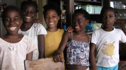 Cinco niñas de Santo Tomé y Príncipe se acercan y sonríen alegremente a la cámara.
