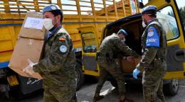 Des hommes de la Force intérimaire des Nations Unies au Liban déchargent un camion contenant des produits de première nécessité. Ils portent des tenues miliatires et des masques de protection.