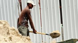 A labourer shoveling sand at a construction site.