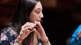Une jeune femme joue de la flûte au sein d'un orchestre de jeunes musiciens.