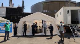 UN personnel and local officials and partners stand outside wearing PPE and social distancing in front of a donated tent to Sta. Ana Hospital for triage patients.