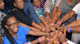 Un grupo de mujeres y hombres juntaron sus brazos para mostrar su solidaridad con el compromiso de acabar con la violencia de género en Trinidad y Tobago.
