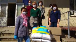 Los trabajadores esenciales y el personal de la ONU permanecen en el exterior junto a los suministros donados, mientras llevan máscaras faciales y mantienen la distancia social.