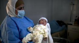 Medical staff at a medical facility at the Azraq Camps holds up a newborn baby.