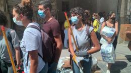 Jóvenes voluntarios caminan juntos con equipo y suministros mientras usan máscaras protectoras.