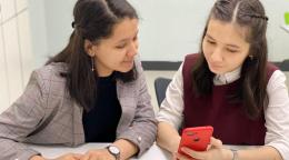 Une fille apprend à se servir des outils technologiques de son téléphone avec sa professeure.
