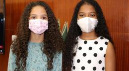 Anyah Spencer Maia y Victoria Roberts Gonçalves Gomes, de 10 años, se paran uno al lado del otro frente a la cámara con mascarillas faciales.