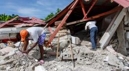 Deux hommes examinent les décombres d'un bâtiment détruit par le séisme de magnitude 7,2 qui a frappé Haïti le 24 août 2021.