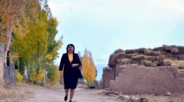 一个身穿黑色西装和黄色衬衫的女人昂首阔步走在路上。