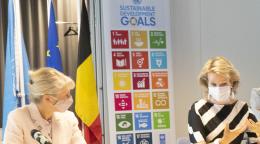 تجلس مديرة مكتب الأمم المتحدة / برنامج الأمم المتحدة الإنمائي في بروكسل إلى جانب صاحبة الجلالة على مكتب أمام الميكروفونات.