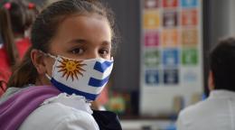 一个女孩戴着带有乌拉圭国旗的口罩，看着镜头。