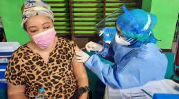 Un profesional sanitario administra a una mujer refugiada, con mascarilla, su primera inyección de la vacuna contra la COVID-19.