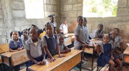 A group of school children near their desks inside a school. 