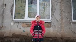 On 6 February 2022, a nine-year-old girl stands in front of the conflict-damaged exterior of her home in eastern Ukraine.