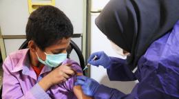 Un pequeño con mascarilla recibe una vacuna contra la COVID-19 en un asentamiento en Saveh, Teherán.