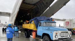 Personas cargando suministros en un avión en la zona del hangar.
