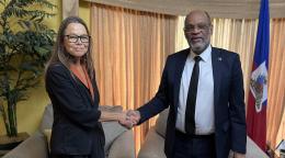 Ulrika Richardson, new UN Deputy Special Representative in Haiti, and the Haitian Prime Minister, Ariel Henry, shake hands in an office with the Haitian flag in the background.