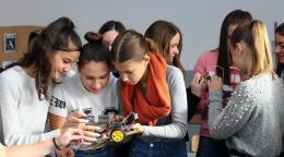 A group of school girls working on a robot car model. 