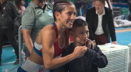 A female boxer embraces a young fan with a fist bump.