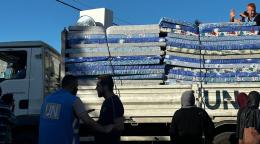 A big UN truck with mattresses stands as people try to unload
