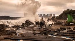 Мужчина на велосипеде едет по дороге, разрушенной землетрясением