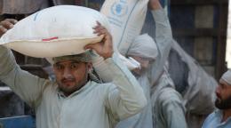 Мужчина с мешком муки на голове, гумантиарной помощью от WFP