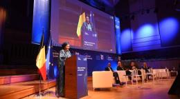DSG Amina J. Mohammed stands behind a lectern and addresses an audience. She on stage with others who are seated at a panel. 