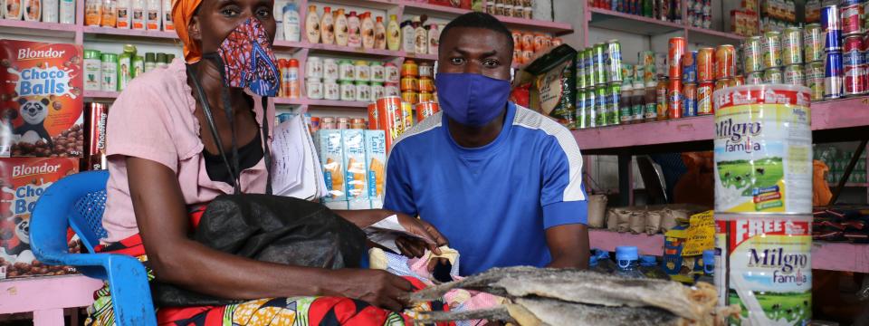 A woman and man wearing face mask sit inside their local market.