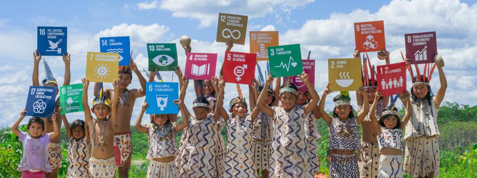 Children hold colorful signs of the SDGs on a sunny day. 