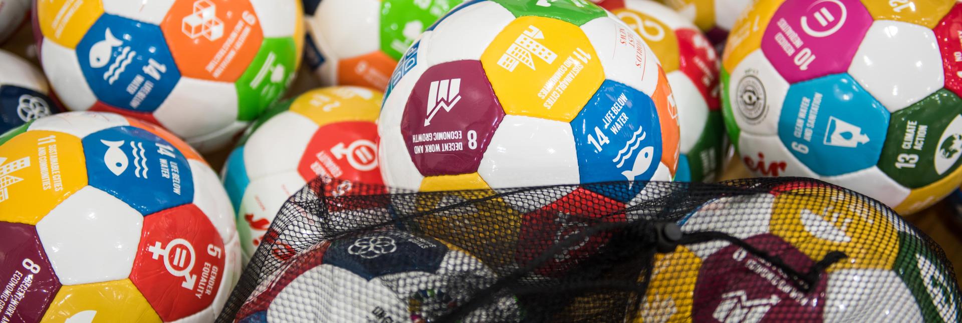 Photo displays a batch of soccer balls with the SDG icons.