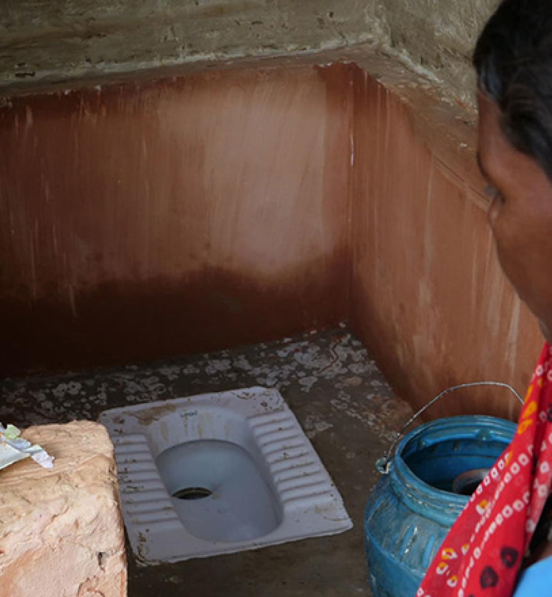 Banner depicts Nepalese woman standing near a toilet built in her village. 