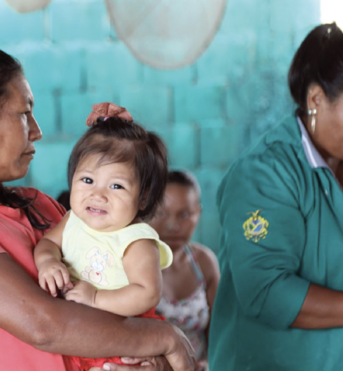 امرأة من الشعوب الأصلية تحمل طفلة وتنتظر حضور العاملة الصحية.
