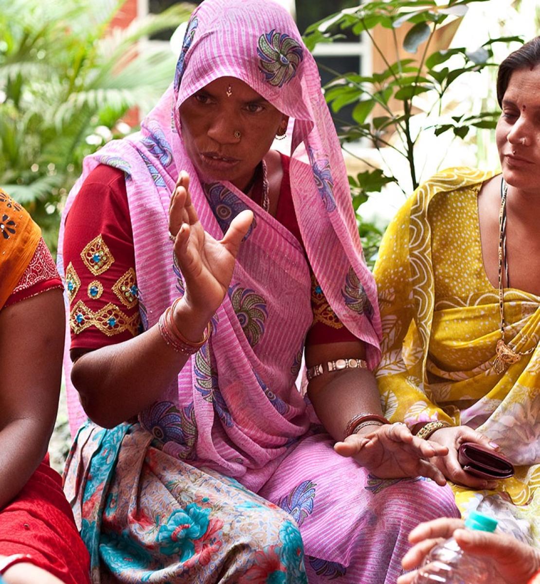 Photo shows a group of Indian women sitting together having a conversation.