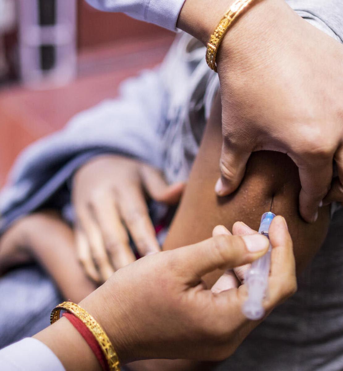 A close up of a medical provider injects a person's arm with the COVID-19 vaccination.