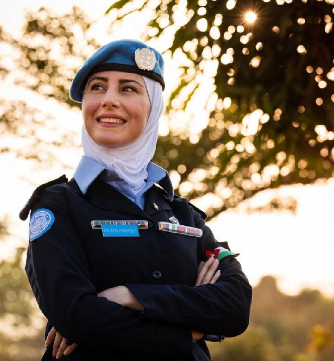 La capitana Ahlam Al-Habahbeh, orgullosa de su uniforme, posa para la cámara al aire libre junto a un árbol.