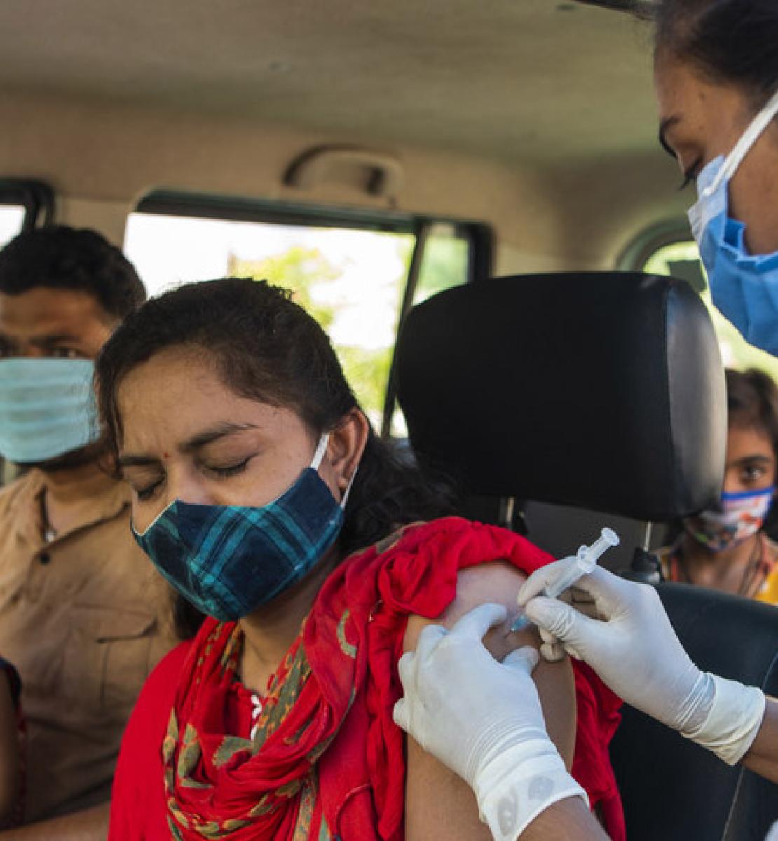 Una mujer cierra los ojos mientras recibe su primera dosis de la vacuna contra la COVID-19 en un centro de vacunación de MP Tourism Motel en Jhabua, Madhya Pradesh.