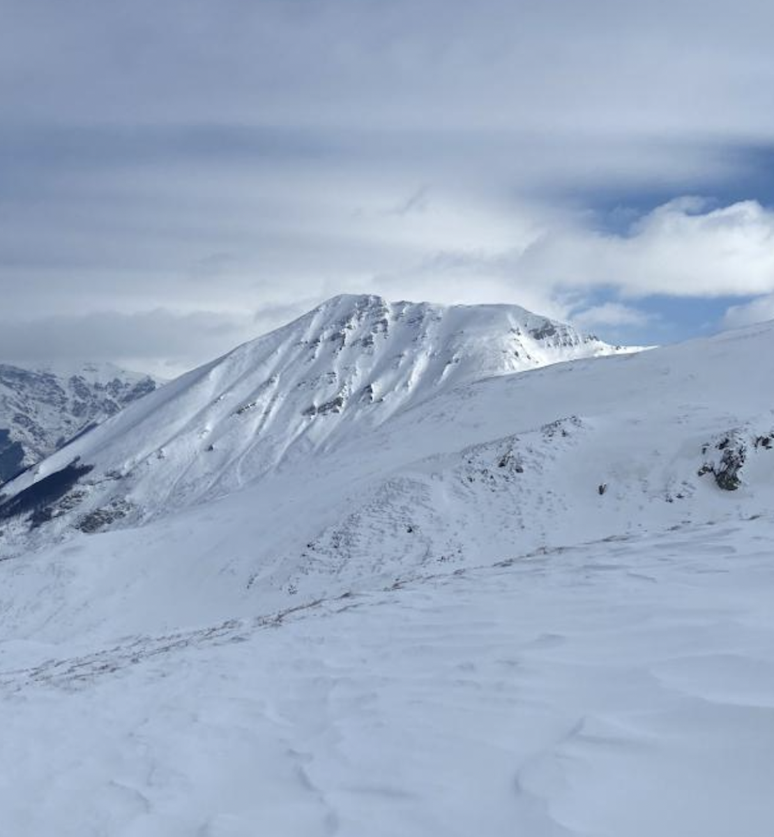 Una imagen de la cima de una montaña nevada en un día nublado.