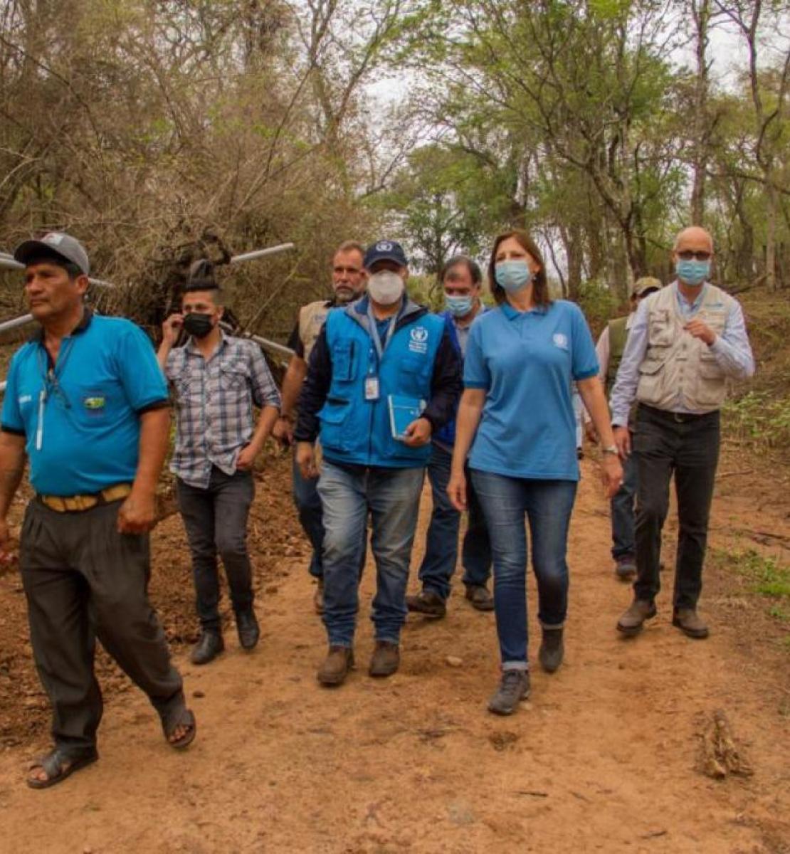 Un grupo de personas con mascarillas caminan juntas por una zona boscosa.