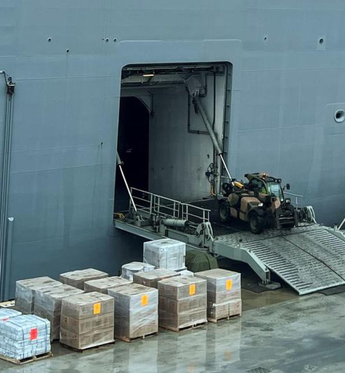 Des ouvriers chargent un navire de fournitures d'urgence destinées à être acheminées vers les îles Tonga.