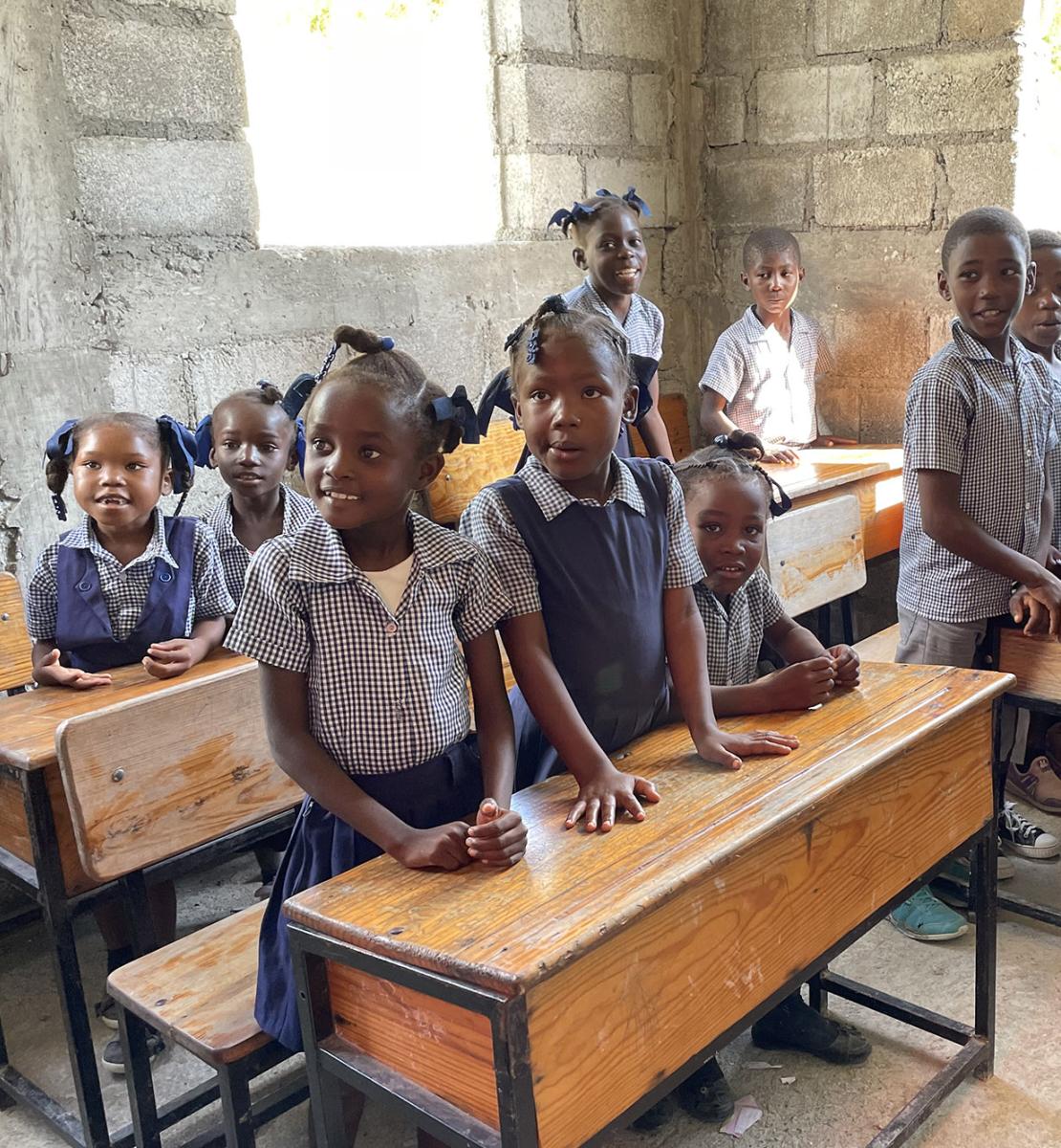 مجموعة من الطلاب بالقرب من طاولاتهم داخل مدرسة.