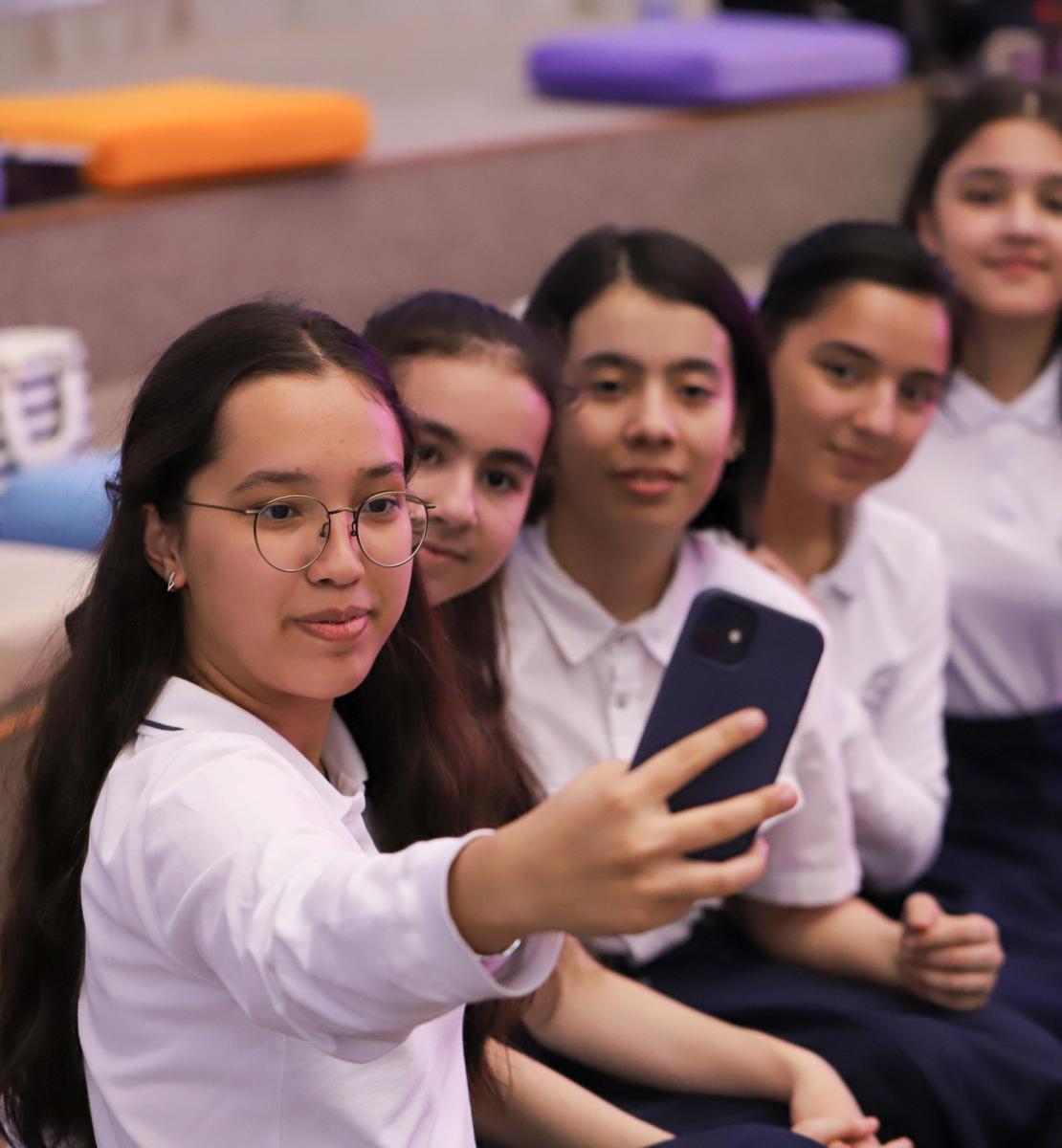 Five girls take a selfie together on a cell phone. 