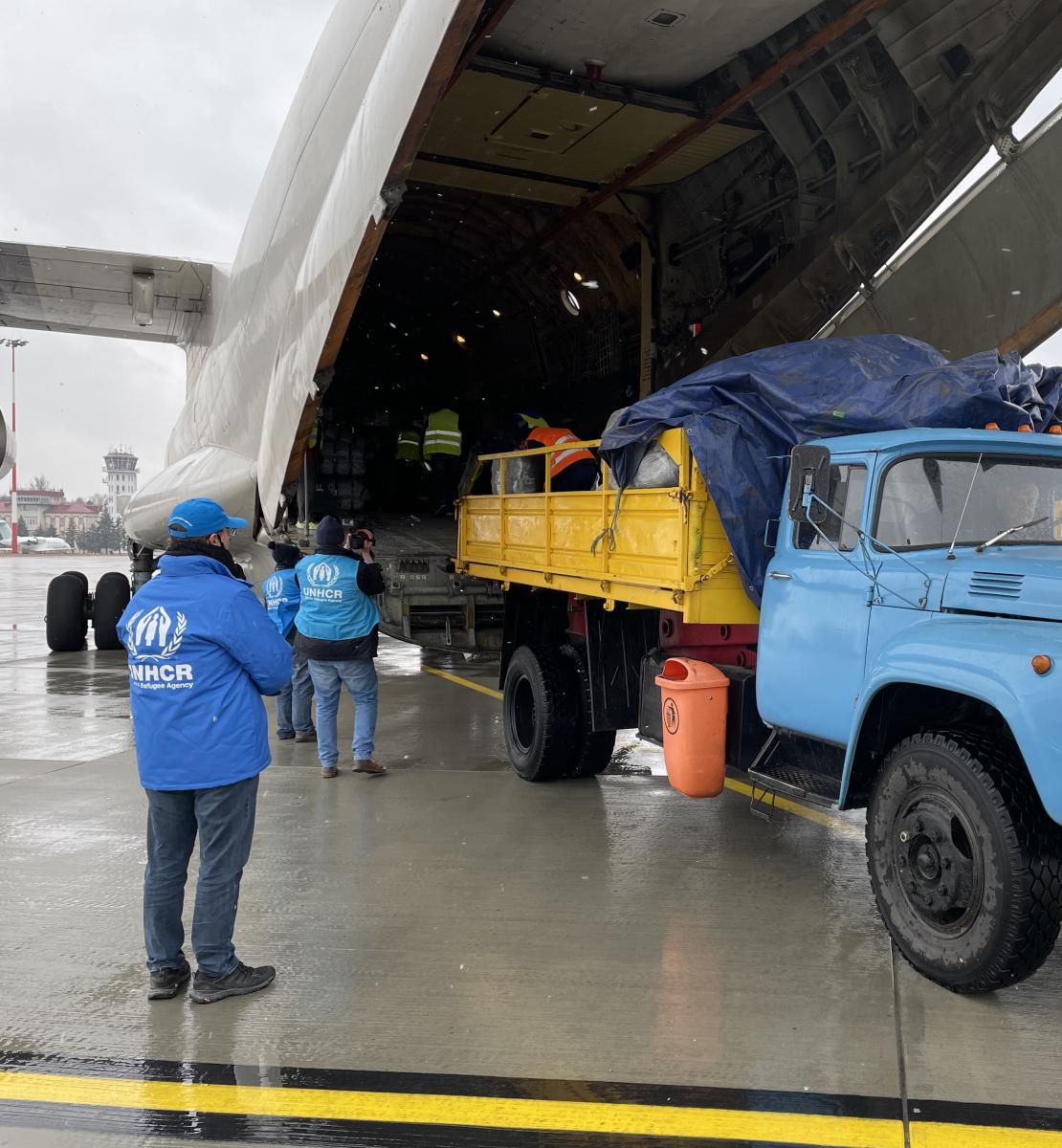 People load supplies onto a plane in the hangar area. 